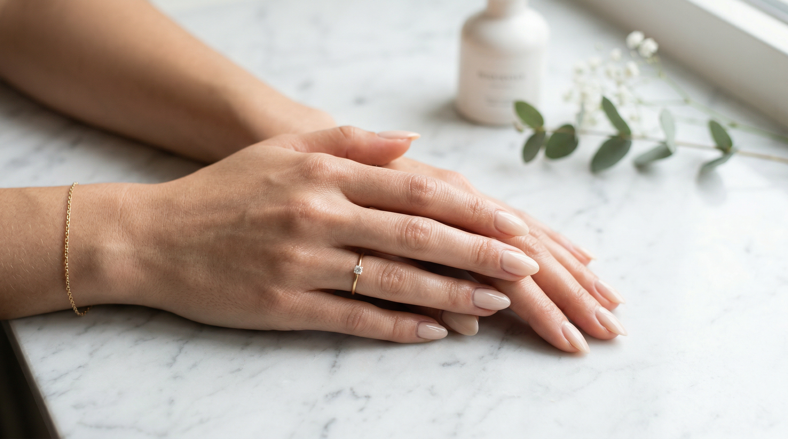 Elegant manicured hands resting on white marble